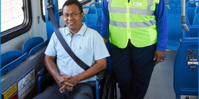 Man in wheelchair exiting a bus with woman by his side